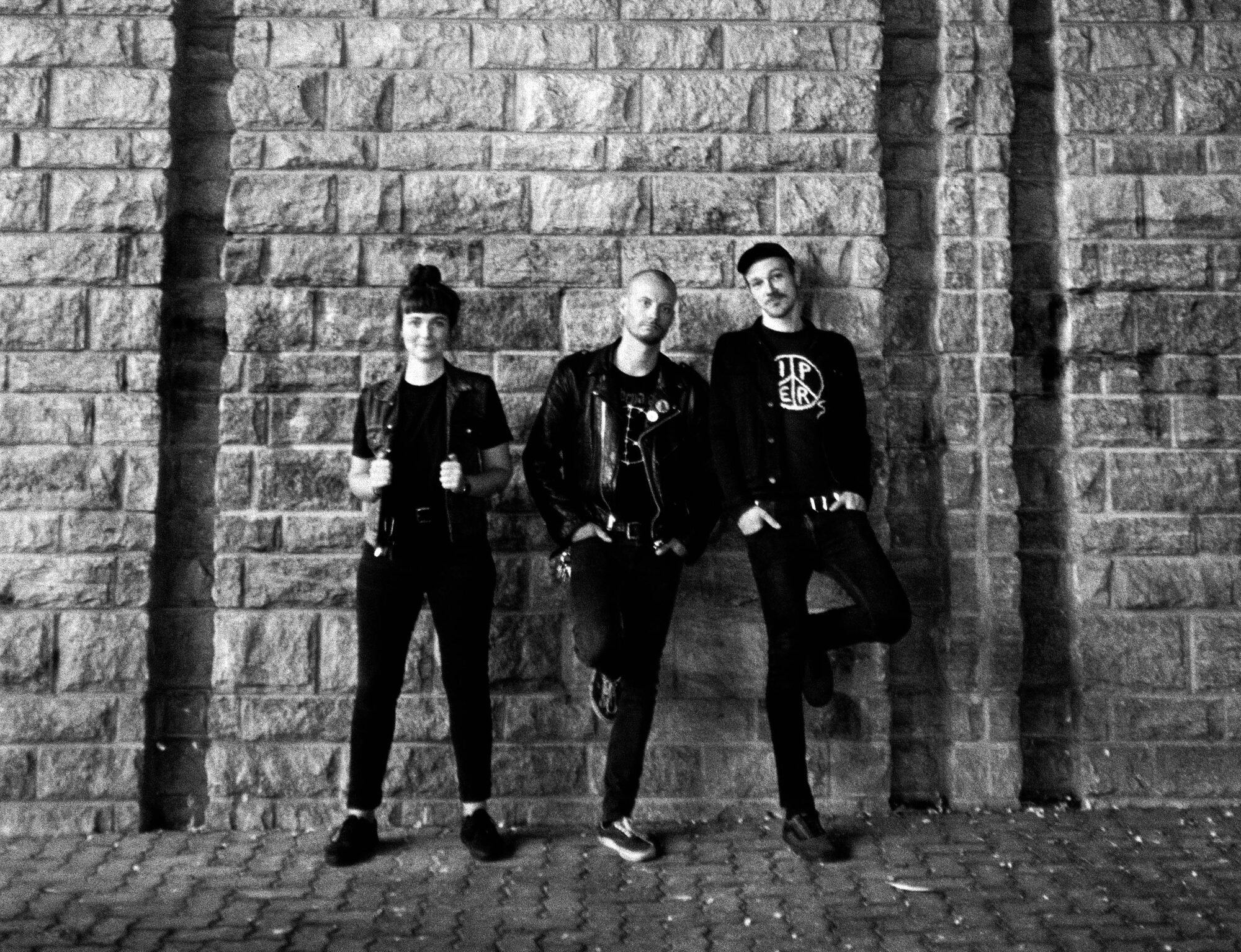 Die drei Mitglieder von Dead Years stehen nebeneinander vor einer Steinwand.