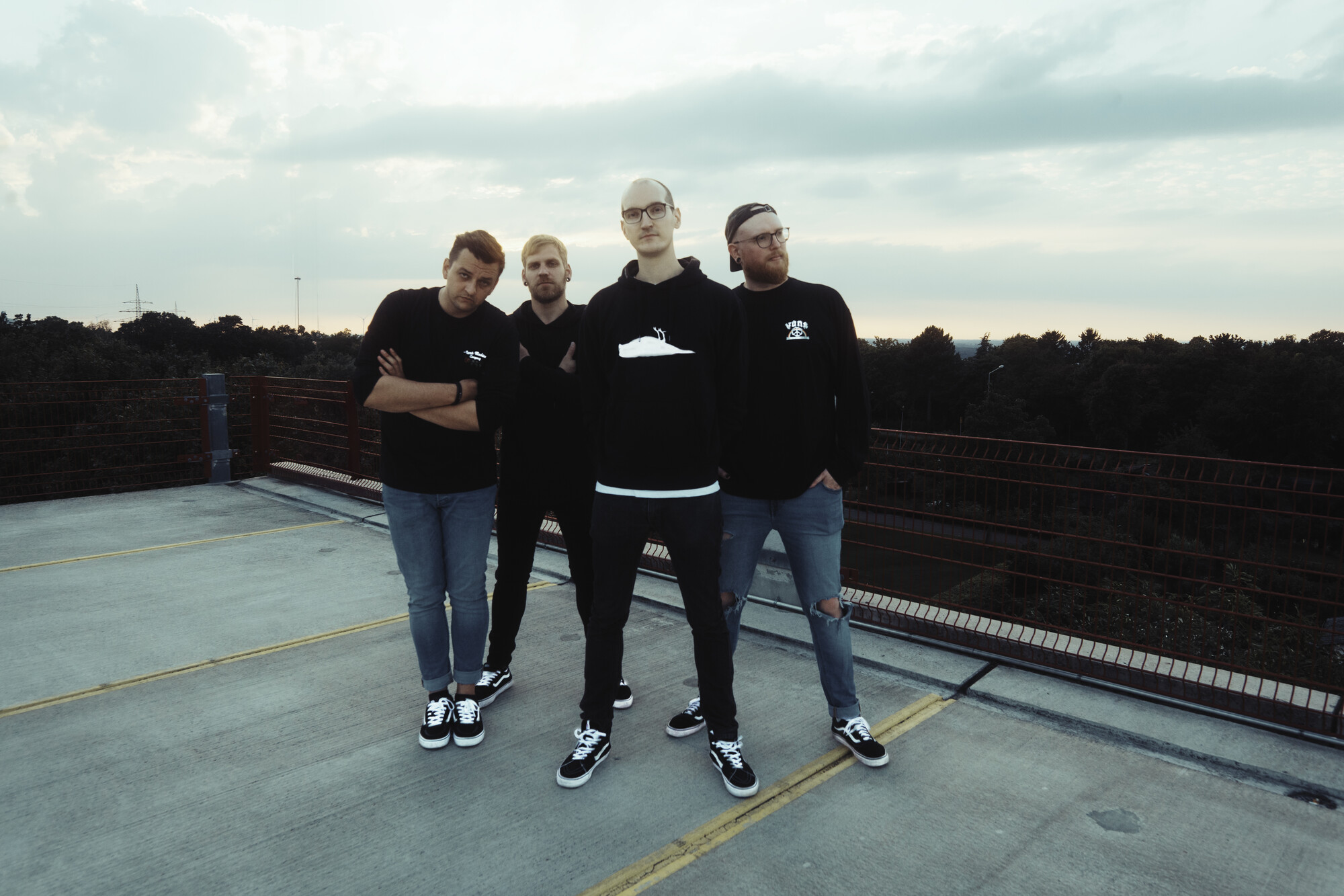 Die vier Mitglieder von Low And Late stehen auf einem Parkdeck vor weitem Himmel.