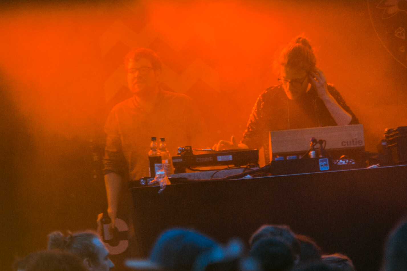 Die DJs von 120 Minuten Party legen bei orangefarbenem Bühnenlicht vor tanzender Menge auf.